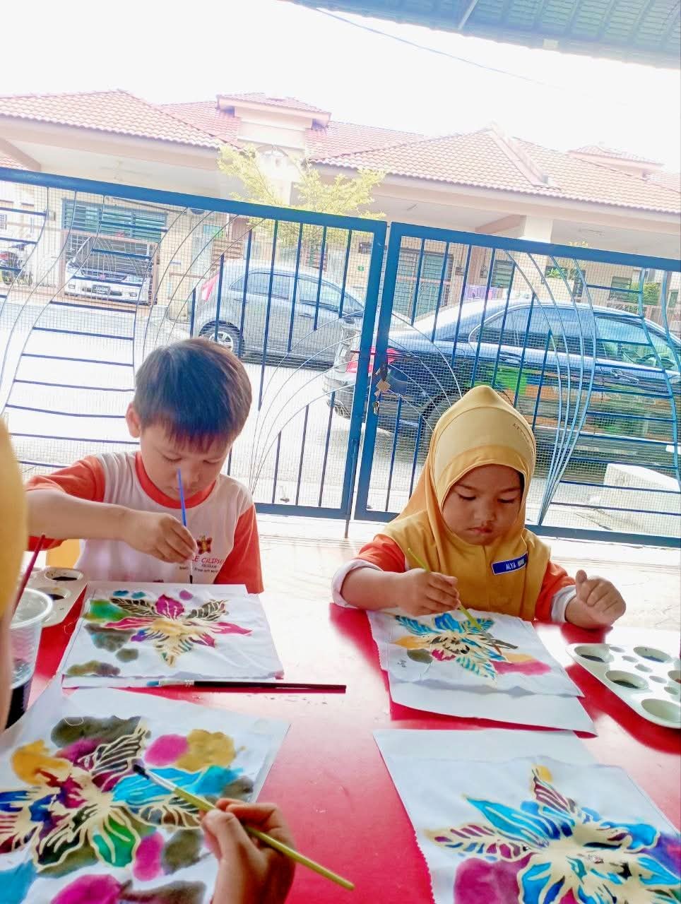 Two children painting butterfly batik panels in bright dyes